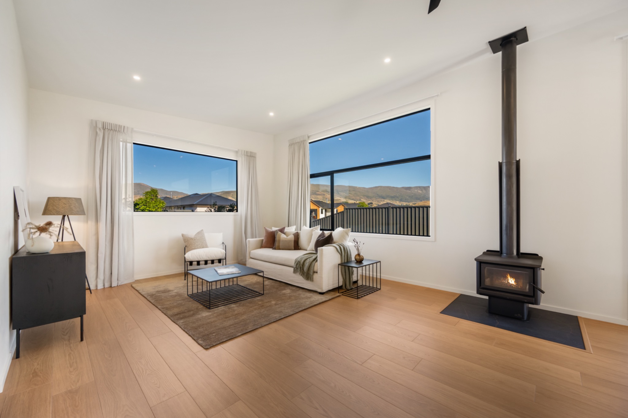 Light-filled living room with timber floors, white walls and a wood burner