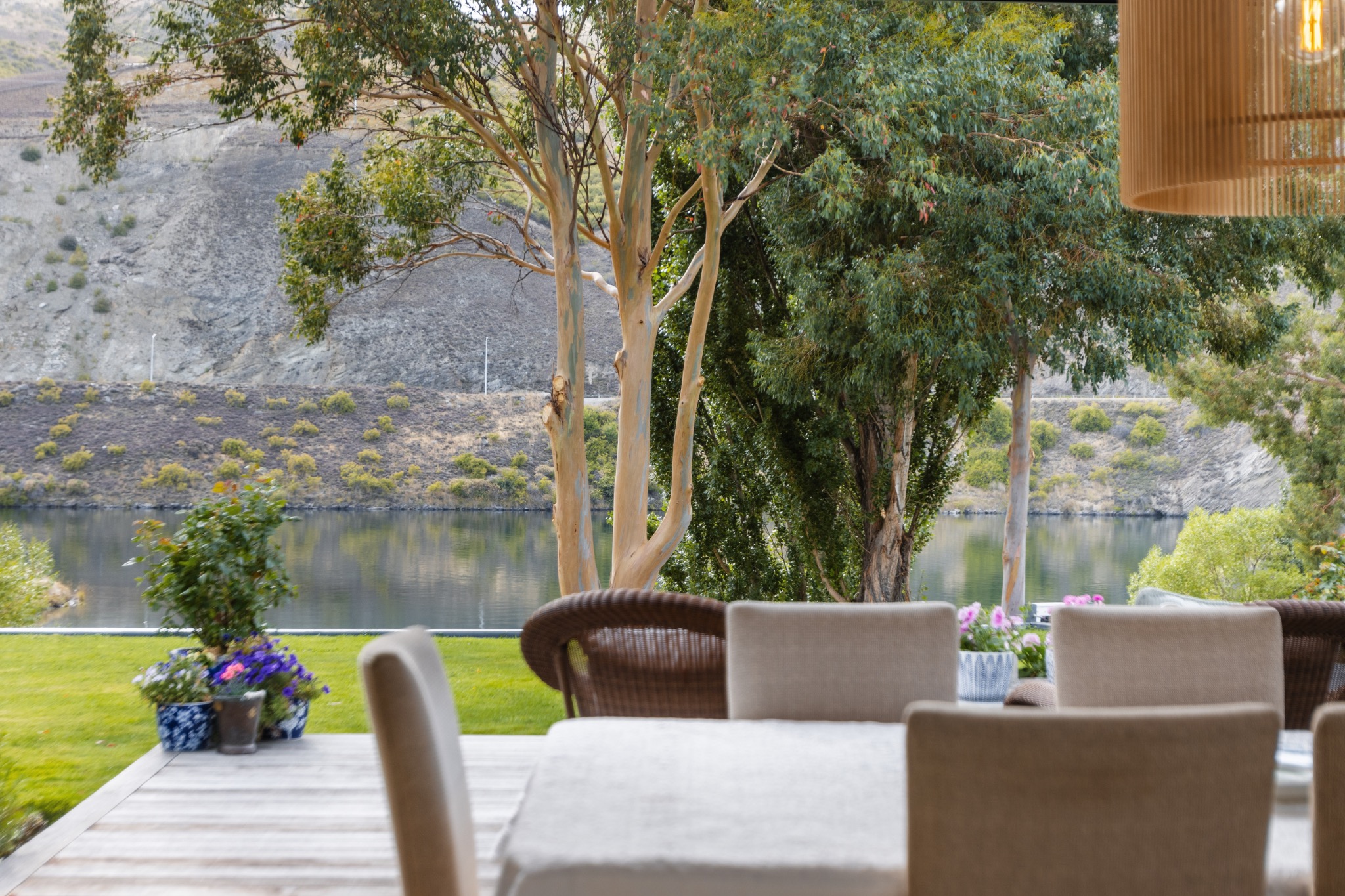 Dining table and chairs beside an open view of trees and water