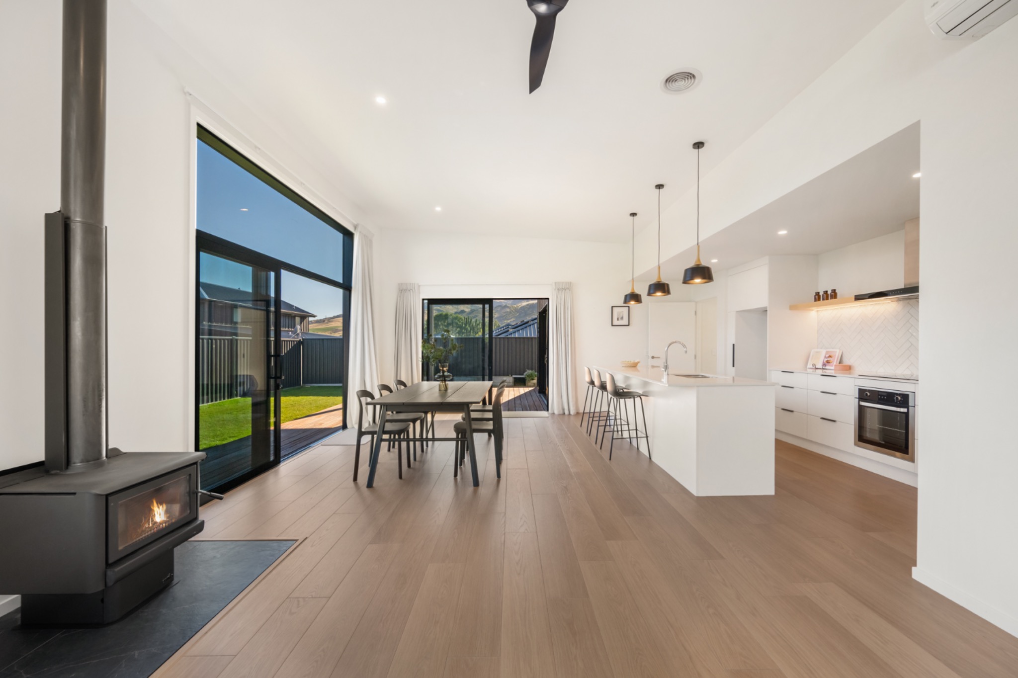 Open-plan dining and kitchen in pale timber and white, opening to the garden