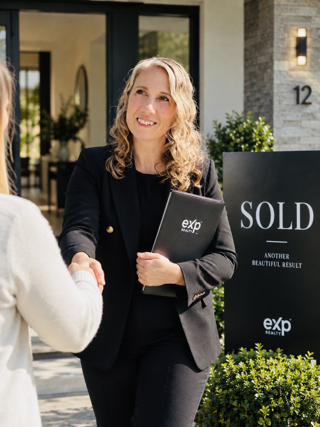 Jasmine Rohland in a black blazer shaking hands with a client outside a home
