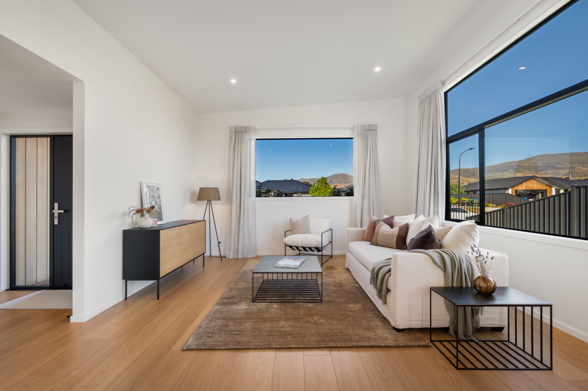 Pale timber and white living room with large windows to the hills