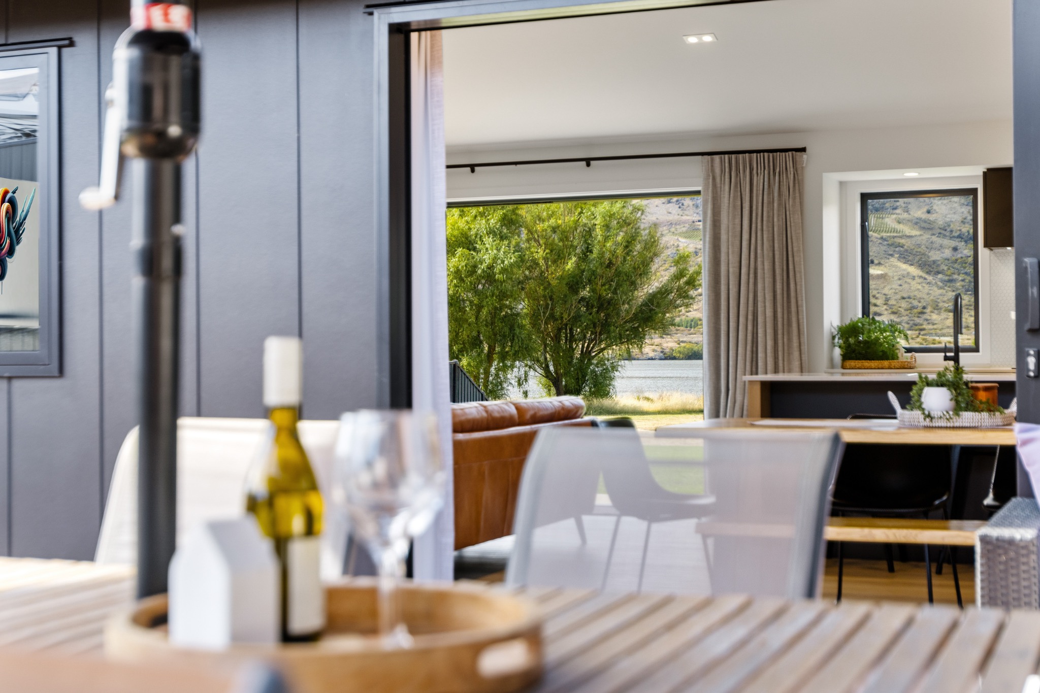 Outdoor dining area opening into a contemporary living space with a water view